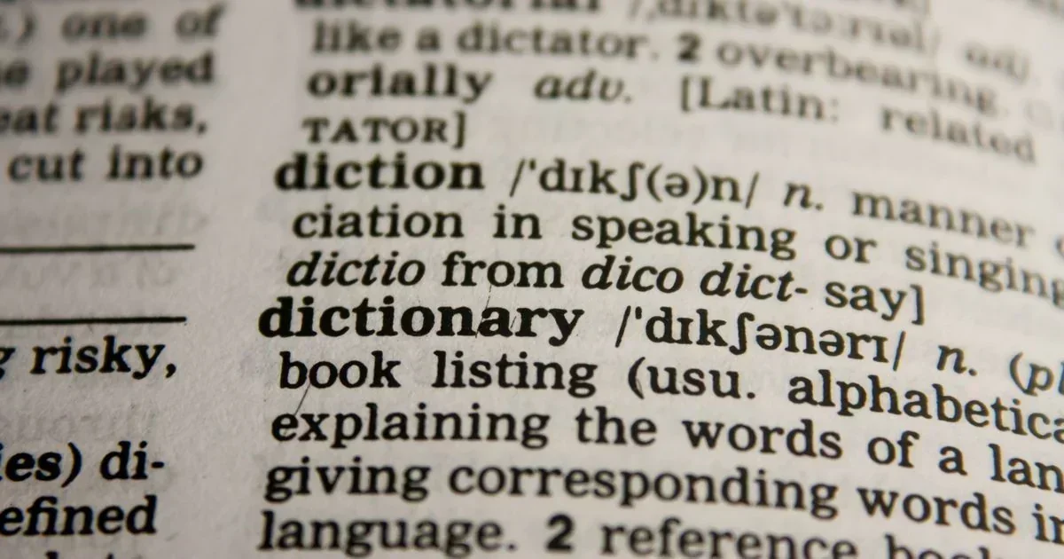 Close-up of a printed dictionary page showing bold entries for diction and dictionary with phonetic spellings and definitions.